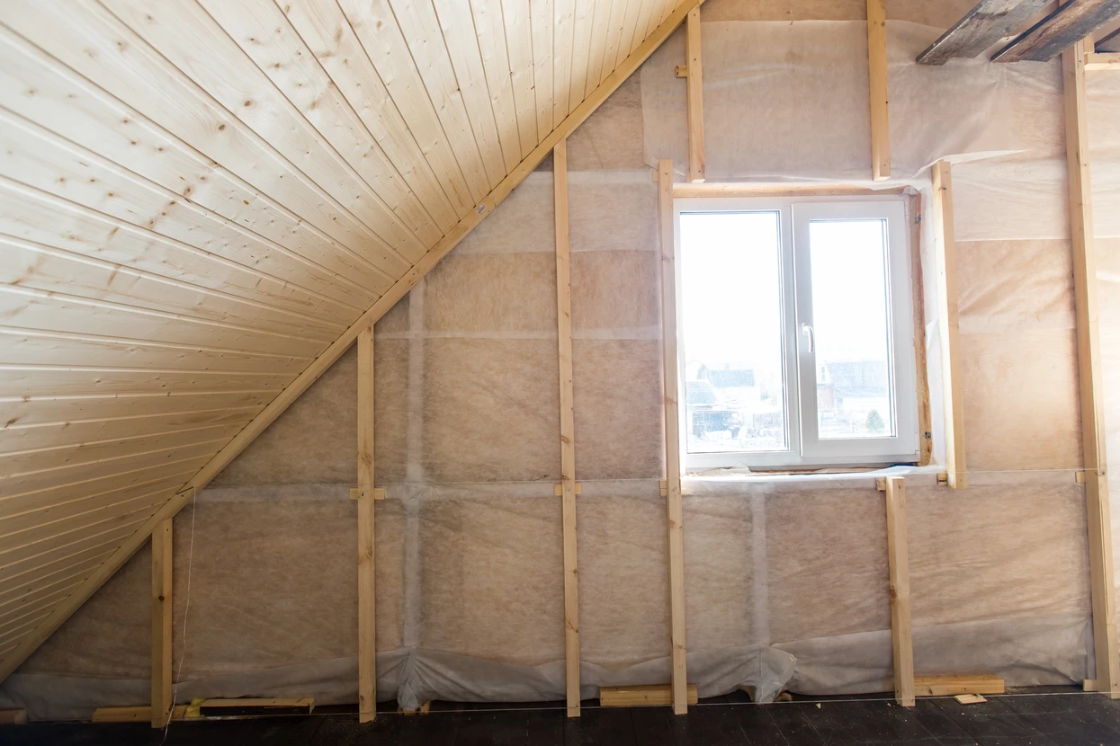 Combles en cours d'isolation thermique avec ossature bois apparente et fenêtre de toit installée