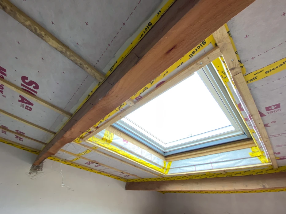 Vue intérieure d'une toiture en cours d'aménagement, avec fenêtre de toit VELUX installée