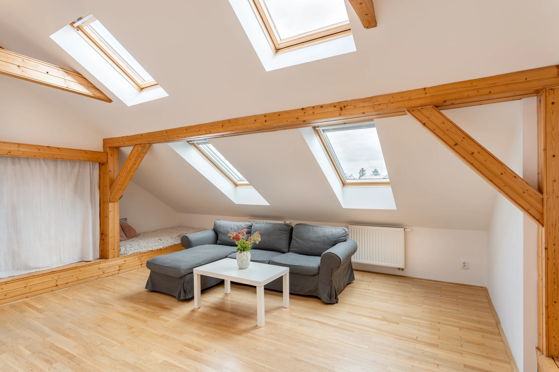 Combles aménagés en cours de finition avec escalier escamotable bois, cartons de déménagement et parquet flottant en cours de pose