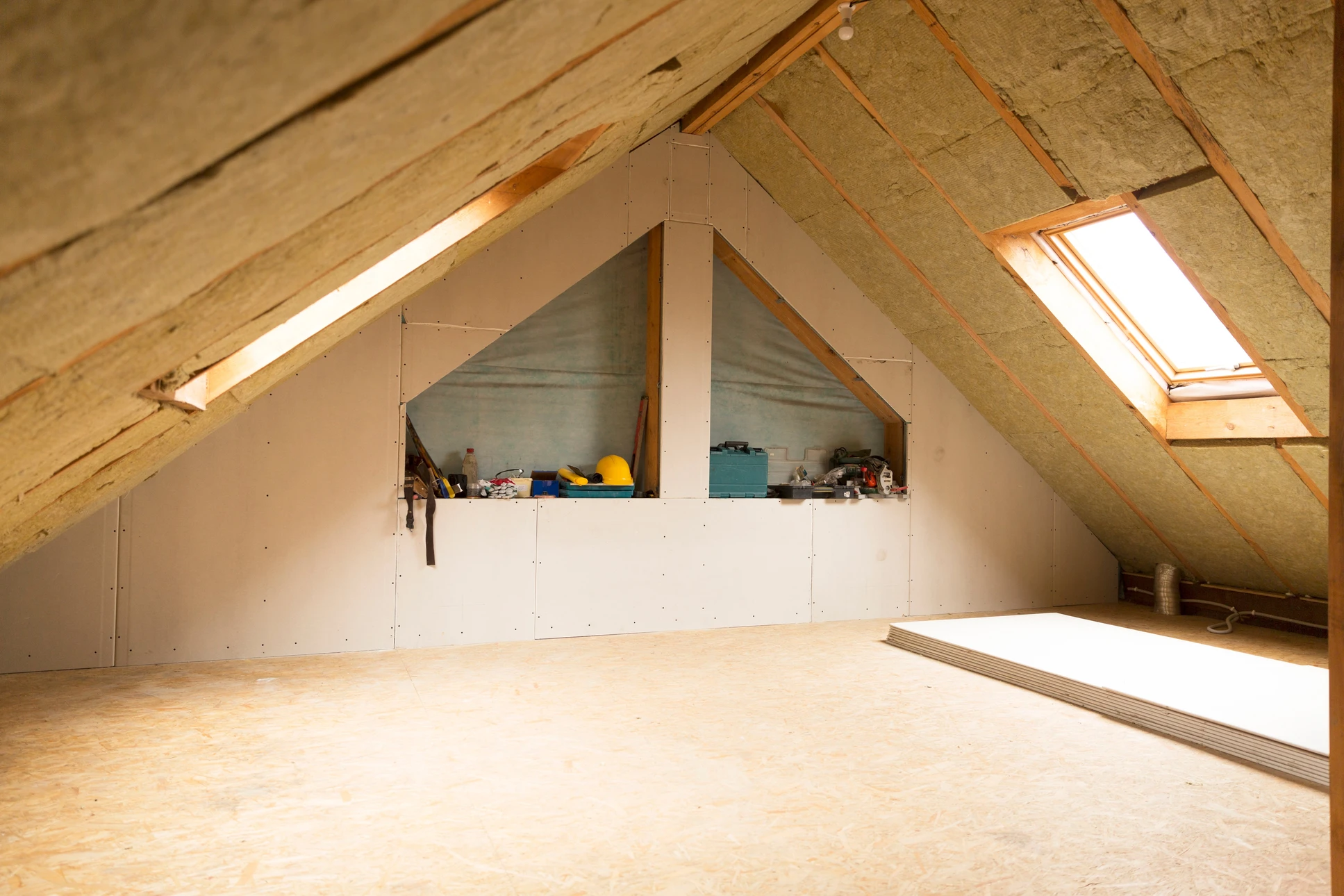 Chantier de rénovation dans combles avec ouvrier installant cloisons sèches