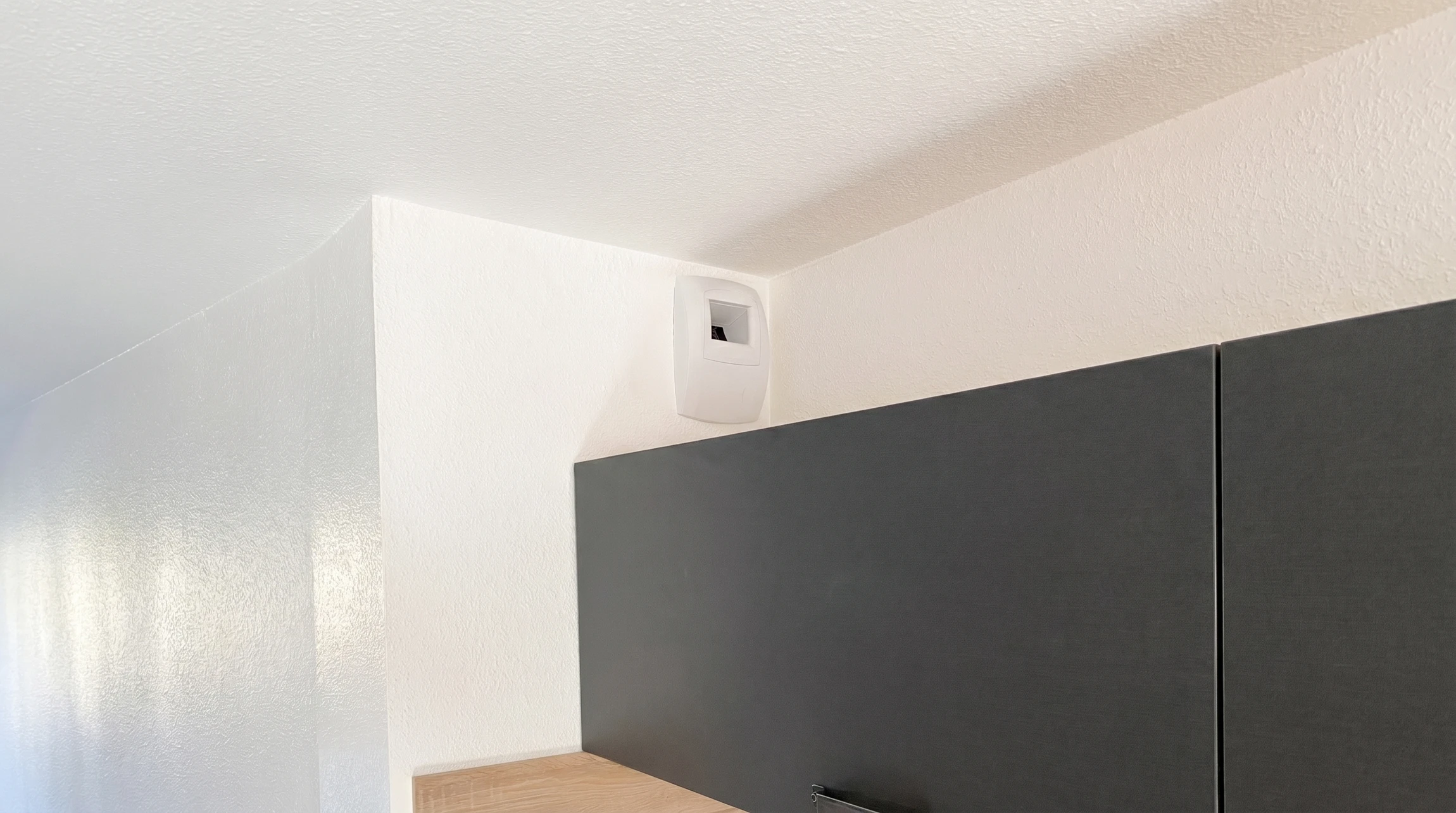 Un technicien installe ou répare une bouche d'aération carrée au plafond d'un intérieur résidentiel
