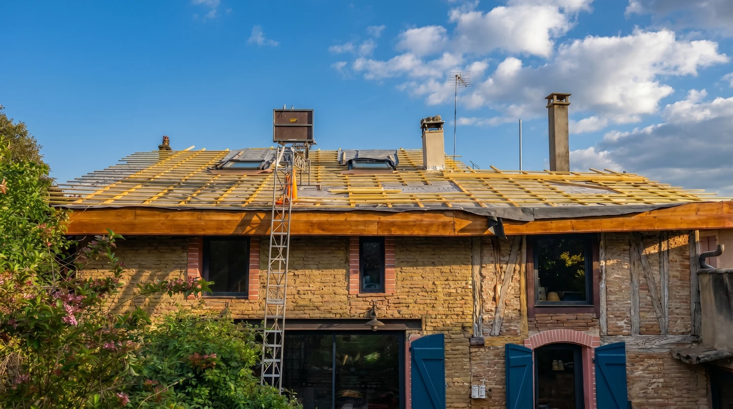 Combles en cours d'isolation thermique avec ossature bois apparente et fenêtre de toit installée