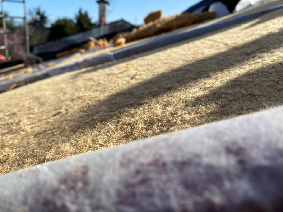 Ouvrier en combinaison à carreaux travaille dans les combles d'une habitation, installant ou réparant un système de ventilation