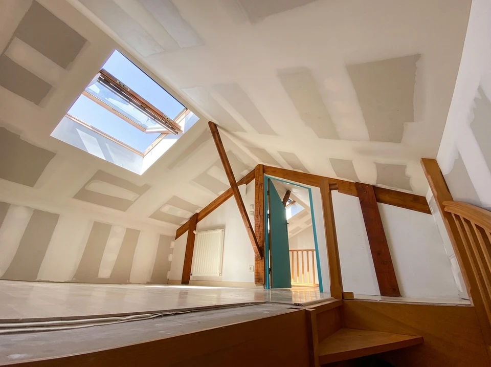 Installateur en gants de protection blancs et bleus positionnant une grille d'aération ventilation dans plafond blanc d'intérieur résidentiel