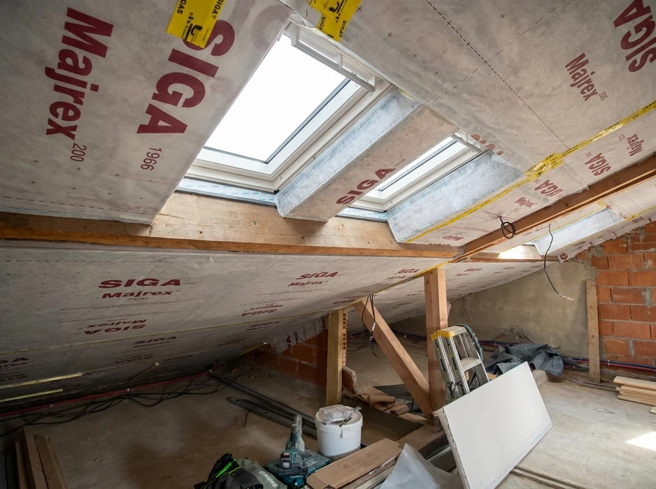Vue intérieure en contre-plongée d'une fenêtre de toit VELUX à cadre en bois de pin naturel, avec store enrouleur intégré